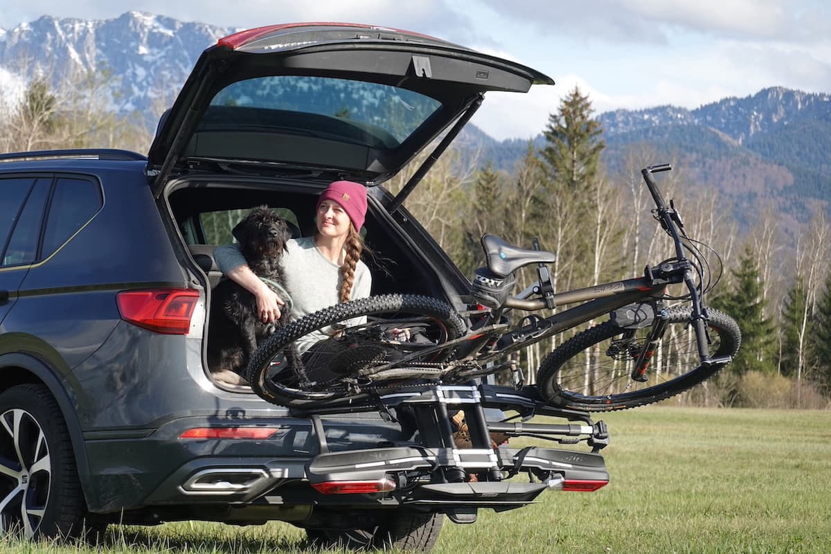 Thule Epos Fahrradträger für die Anhängerkupplung mit geöffnetem Kofferraum vor Bergkulisse